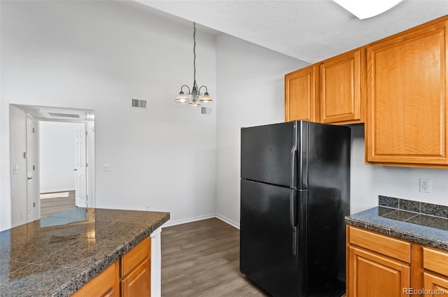 kitchen featuring light hardwood / wood-style flooring, decorative light fixtures, a textured ceiling, a notable chandelier, and black fridge