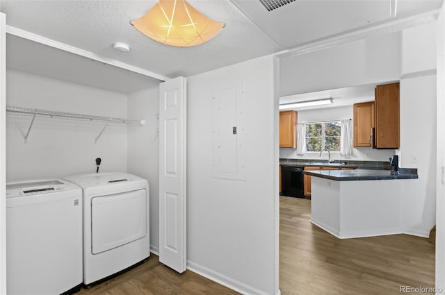 clothes washing area with separate washer and dryer, a textured ceiling, dark wood-type flooring, sink, and electric panel