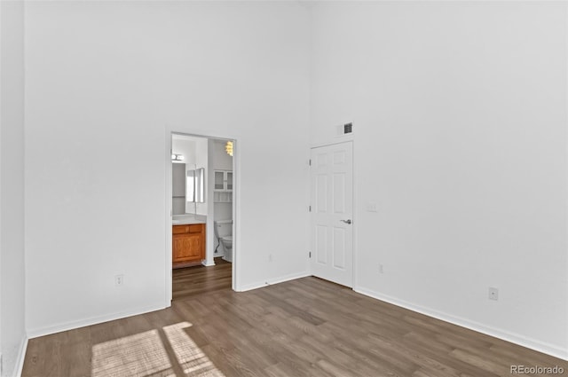 empty room with a high ceiling and dark hardwood / wood-style flooring