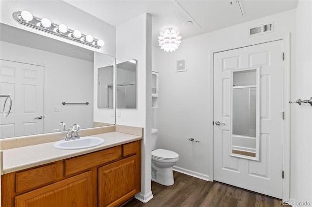 bathroom featuring hardwood / wood-style flooring, toilet, walk in shower, and vanity