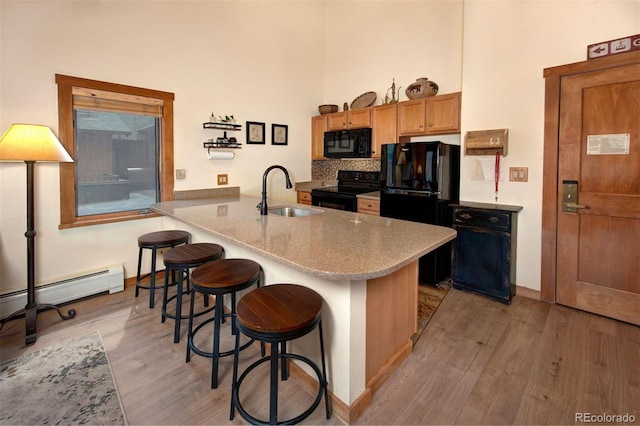 91 River Run Rd Unit 8140, Keystone, CO 80435 - kitchen featuring black appliances, a sink, light wood-style floors, a kitchen bar, and a towering ceiling