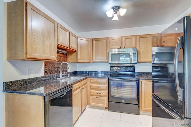 kitchen with light tile patterned flooring, sink, dark stone counters, black appliances, and a textured ceiling