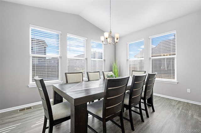 dining space with hardwood / wood-style flooring, a chandelier, a healthy amount of sunlight, and vaulted ceiling