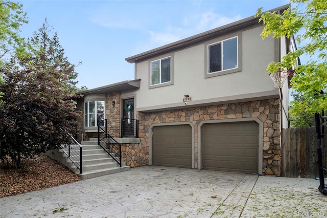 view of front of home featuring a garage, driveway, stone siding, and stucco siding