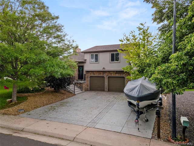 tri-level home featuring a garage, stone siding, driveway, and stucco siding