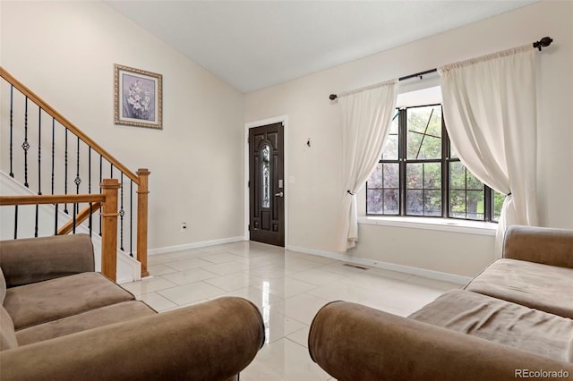 living room featuring lofted ceiling, visible vents, light tile patterned flooring, baseboards, and stairs