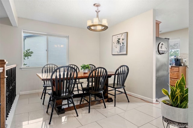 dining room featuring an inviting chandelier, light tile patterned floors, baseboards, and a textured ceiling