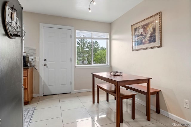 dining area with rail lighting, light tile patterned flooring, and baseboards