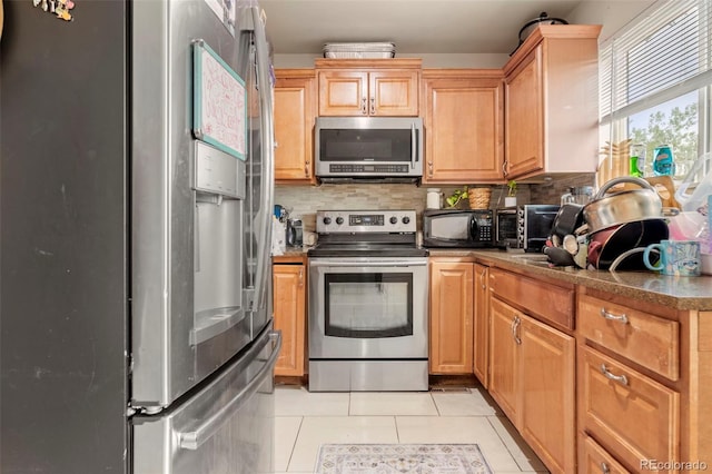 kitchen featuring light tile patterned floors, appliances with stainless steel finishes, and backsplash