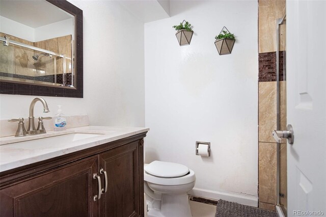 bathroom with a stall shower, baseboards, vanity, and toilet