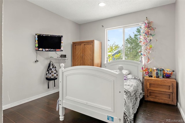 bedroom featuring a textured ceiling, baseboards, and dark wood-type flooring