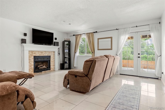 living room featuring a textured ceiling, a stone fireplace, french doors, and light tile patterned flooring