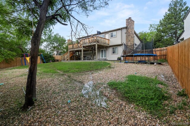 back of property featuring a playground, a fenced backyard, stairway, stucco siding, and a trampoline