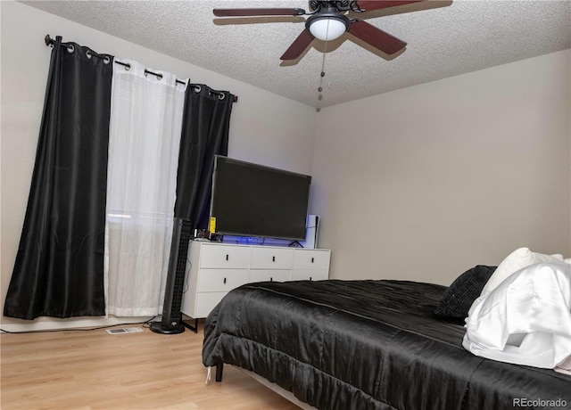 bedroom with visible vents, light wood-style floors, ceiling fan, and a textured ceiling