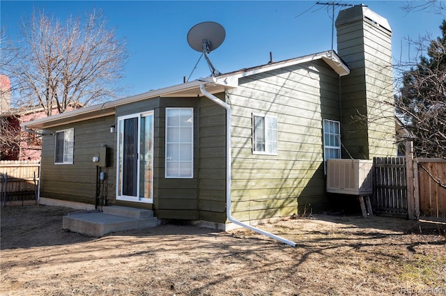 back of house featuring fence and a chimney