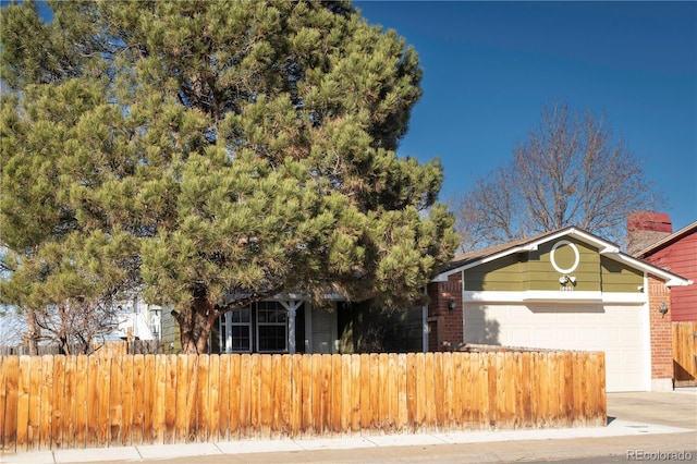 view of front of house with brick siding, an attached garage, concrete driveway, and fence