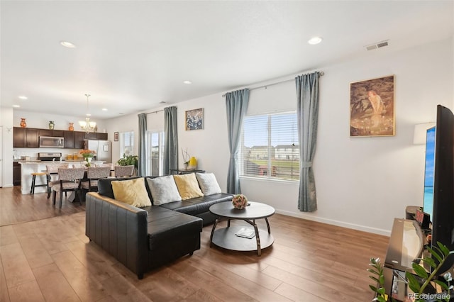 living room with a notable chandelier and light wood-type flooring