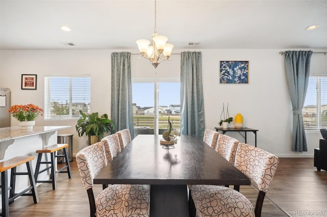 dining room with an inviting chandelier, hardwood / wood-style flooring, and a healthy amount of sunlight