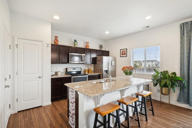 kitchen featuring a center island with sink, a breakfast bar area, dark wood-type flooring, sink, and stainless steel appliances