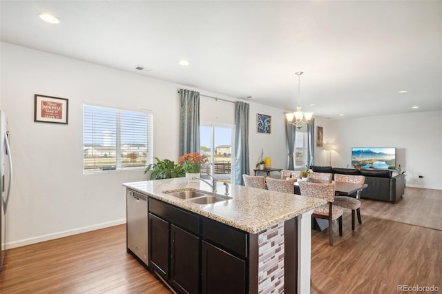 kitchen with dishwasher, sink, pendant lighting, light wood-type flooring, and a chandelier