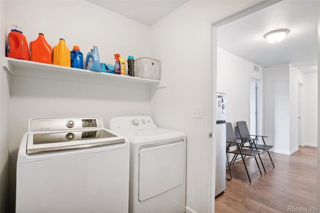 clothes washing area featuring light hardwood / wood-style flooring and separate washer and dryer