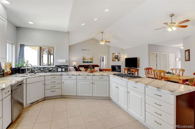 kitchen featuring appliances with stainless steel finishes, sink, white cabinets, kitchen peninsula, and lofted ceiling