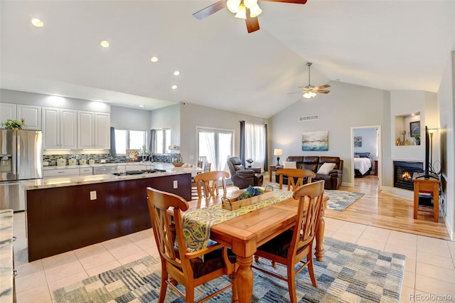 dining area featuring high vaulted ceiling, ceiling fan, and light hardwood / wood-style flooring