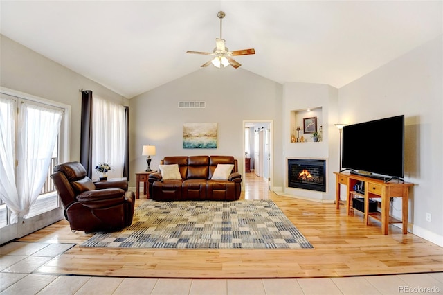 living room with ceiling fan, a wealth of natural light, lofted ceiling, and light hardwood / wood-style floors