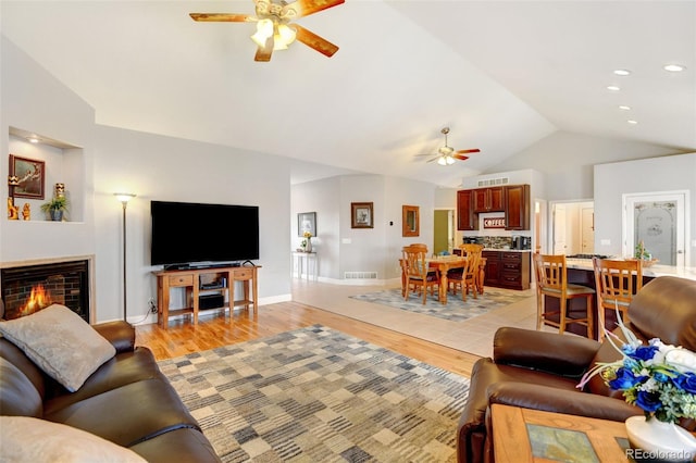 living room with light hardwood / wood-style floors, ceiling fan, and vaulted ceiling