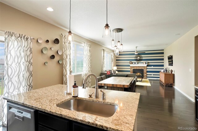 26143 E Fremont Pl, Aurora, CO 80016 - kitchen with a sink, stainless steel dishwasher, open floor plan, a fireplace, and an accent wall
