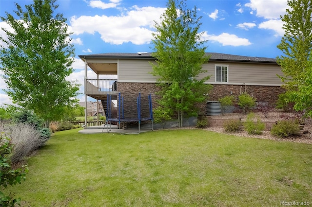 26143 E Fremont Pl, Aurora, CO 80016 - rear view of house featuring a trampoline, stone siding, stairway, and a yard