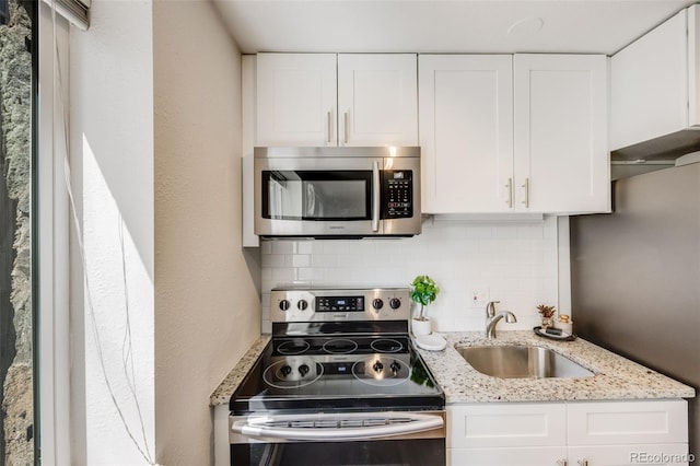 1349 Race St Unit 5, Denver, CO 80206 - kitchen with stainless steel appliances, a sink, white cabinetry, tasteful backsplash, and light stone countertops