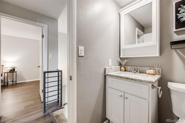 1349 Race St Unit 5, Denver, CO 80206 - half bathroom featuring wood finished floors, vanity, toilet, and a textured wall