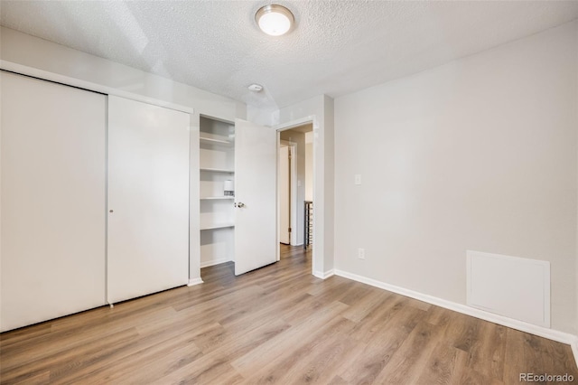 1349 Race St Unit 5, Denver, CO 80206 - unfurnished bedroom with light wood finished floors, a textured ceiling, baseboards, and a closet