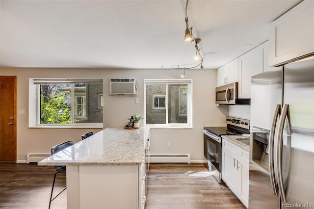 1349 Race St Unit 5, Denver, CO 80206 - kitchen with appliances with stainless steel finishes, baseboard heating, a breakfast bar, and a wall mounted air conditioner