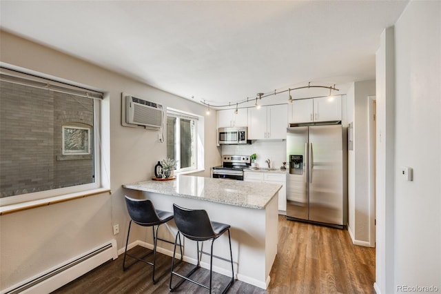 1349 Race St Unit 5, Denver, CO 80206 - kitchen with appliances with stainless steel finishes, baseboard heating, a wall mounted air conditioner, wood finished floors, and white cabinets