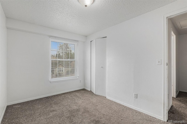 empty room with a textured ceiling, baseboards, and carpet