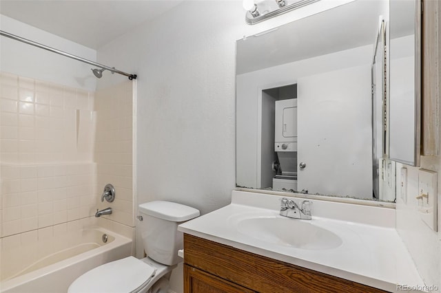 bathroom featuring toilet, shower / bathing tub combination, stacked washer and clothes dryer, and vanity