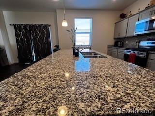 kitchen featuring stainless steel appliances, light stone countertops, backsplash, a sink, and modern cabinets