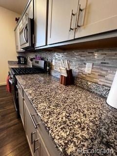 kitchen with dark wood-style floors, appliances with stainless steel finishes, backsplash, and light stone counters