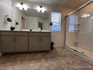 bathroom with double vanity, an enclosed shower, and baseboards