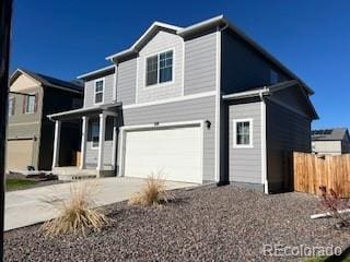 traditional home featuring an attached garage, fence, and concrete driveway