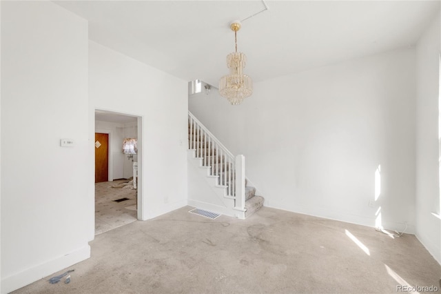 empty room with a chandelier, stairway, visible vents, and baseboards