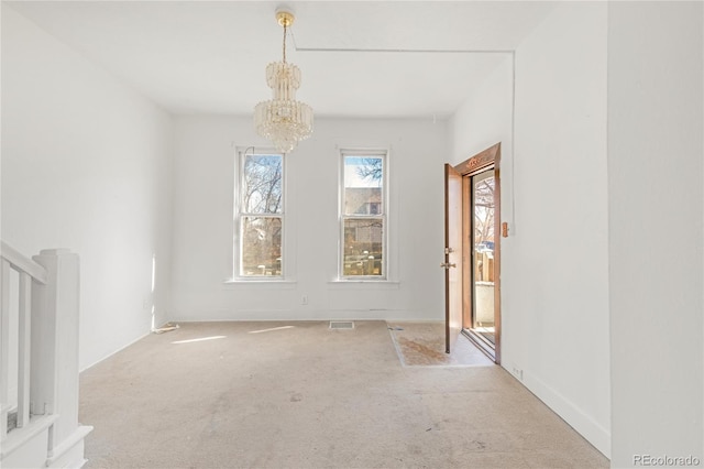 carpeted spare room with an inviting chandelier, baseboards, and visible vents