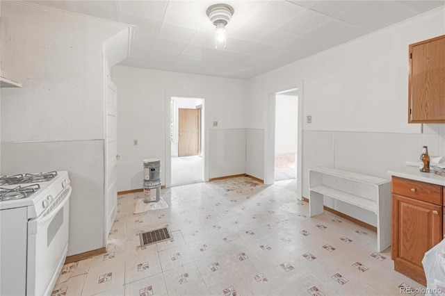 kitchen with light floors, light countertops, visible vents, brown cabinetry, and white range with gas cooktop