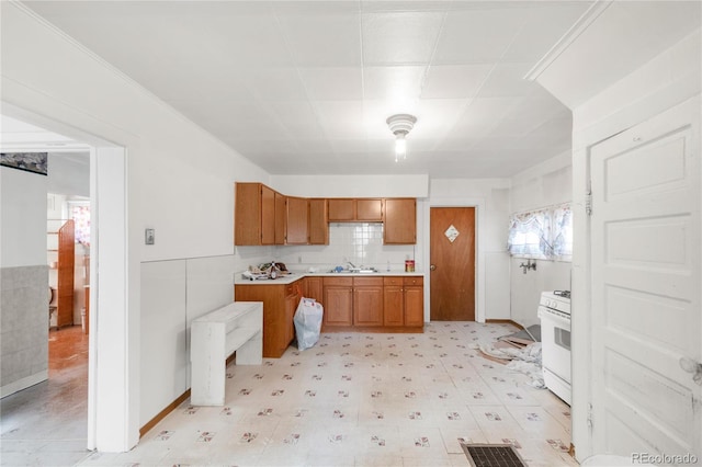 kitchen with white gas stove, a sink, visible vents, light countertops, and brown cabinets