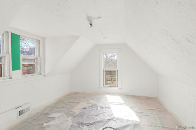 additional living space featuring lofted ceiling, a textured ceiling, visible vents, and a healthy amount of sunlight