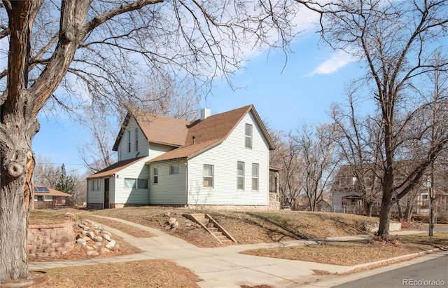 view of property exterior featuring a chimney and roof with shingles