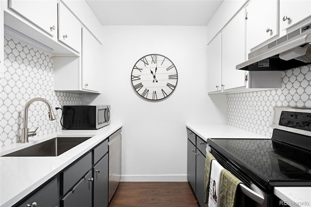 kitchen with decorative backsplash, appliances with stainless steel finishes, light countertops, under cabinet range hood, and a sink