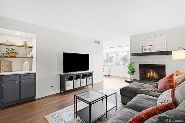 living area with a brick fireplace, baseboards, and dark wood-style flooring